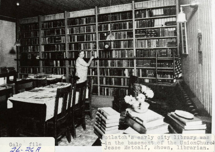 A photograph of Potlatch's early city library in the basement of the Union Church with the librarian Jesse Metcalf.
