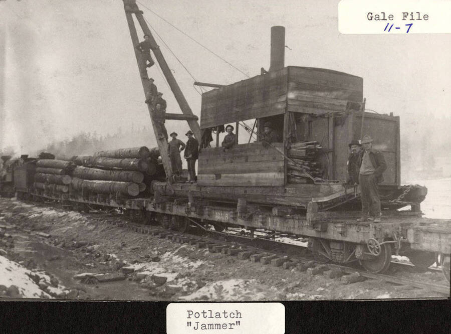 A few men standing on the 'jammer' that was used to haul logs.