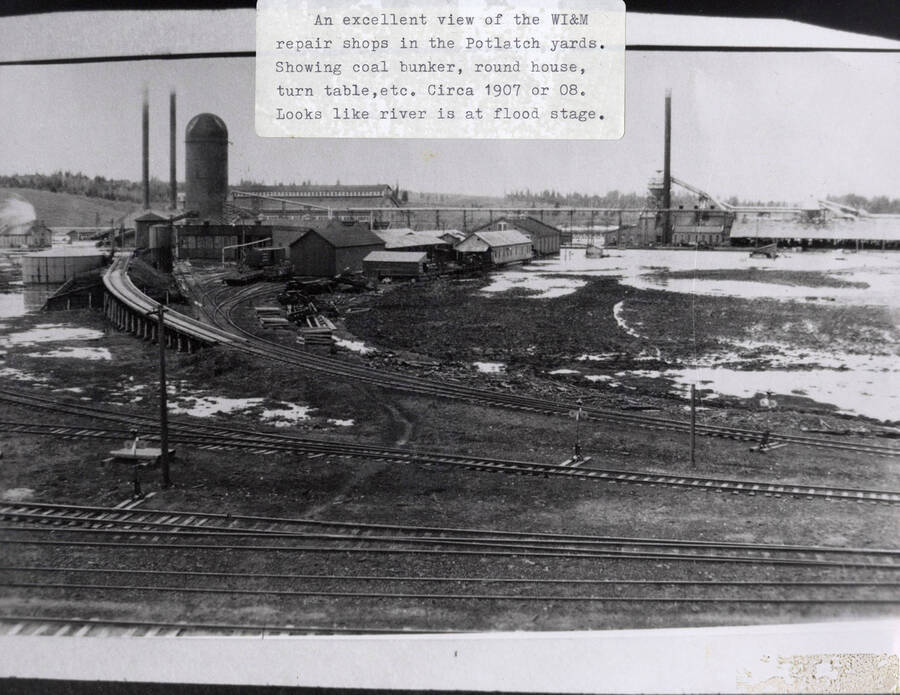 View of the WI&M repair shops in the Potlatch yards. The view shows the coal bunker, the round house, and the turn table. The river can also be seen at flood stage.