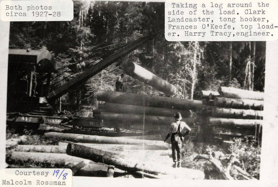 Clark Lancaster (tong hooker), Frances O'Keefe (top loader), and Harry Tracy (engineer) using a jammer to load logs onto flat cars. The log is being taken around the side of the load