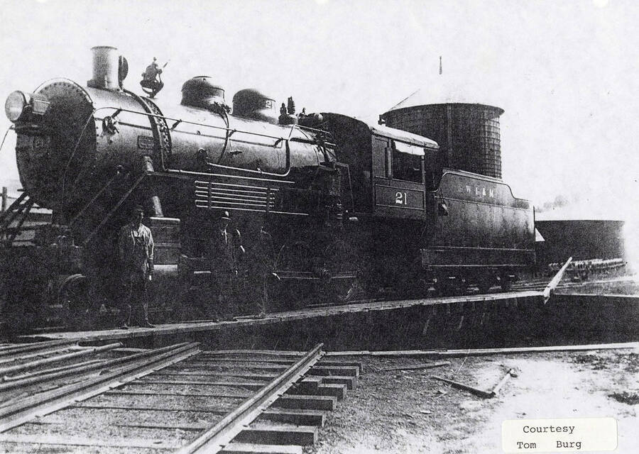 View of a No. 21 locomotive. A few men can be seen standing next to the locomotive.