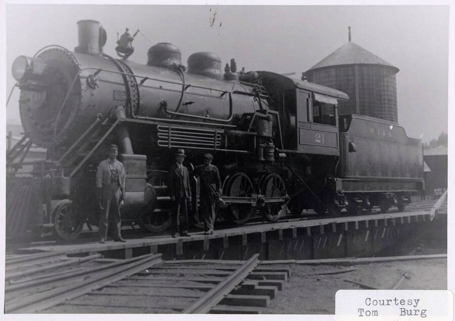 Three men standing next to a No. 21 locomotive.
