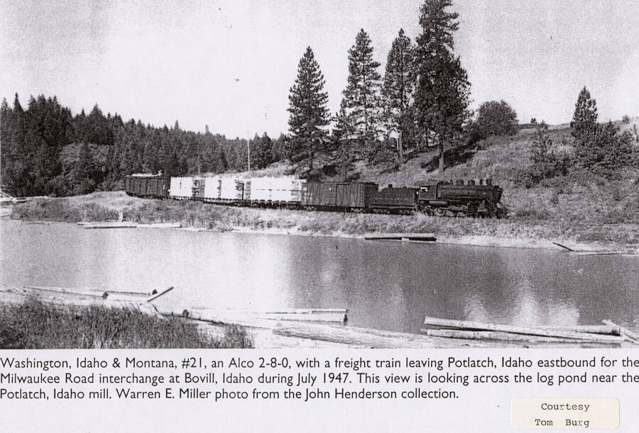 A WI&M No. 21 locomotive leaving Potlatch, Idaho heading eastbound for the Wilwaukee Road interchange at Bovill, Idaho. The view looks across the log pond, which is located jear the Potlatch mill.