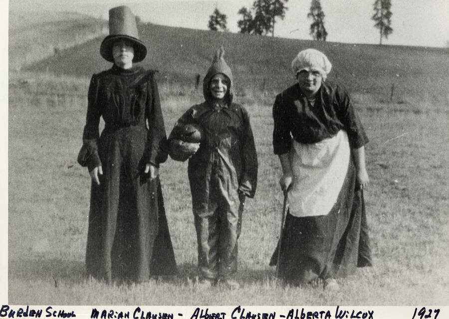 Marian Clausen, Albert Clausen, and Alberta Wilcox standing in a field near the Burden School. Albert is holding a Jack-O-Lantern. Photograph taken in 1927.
