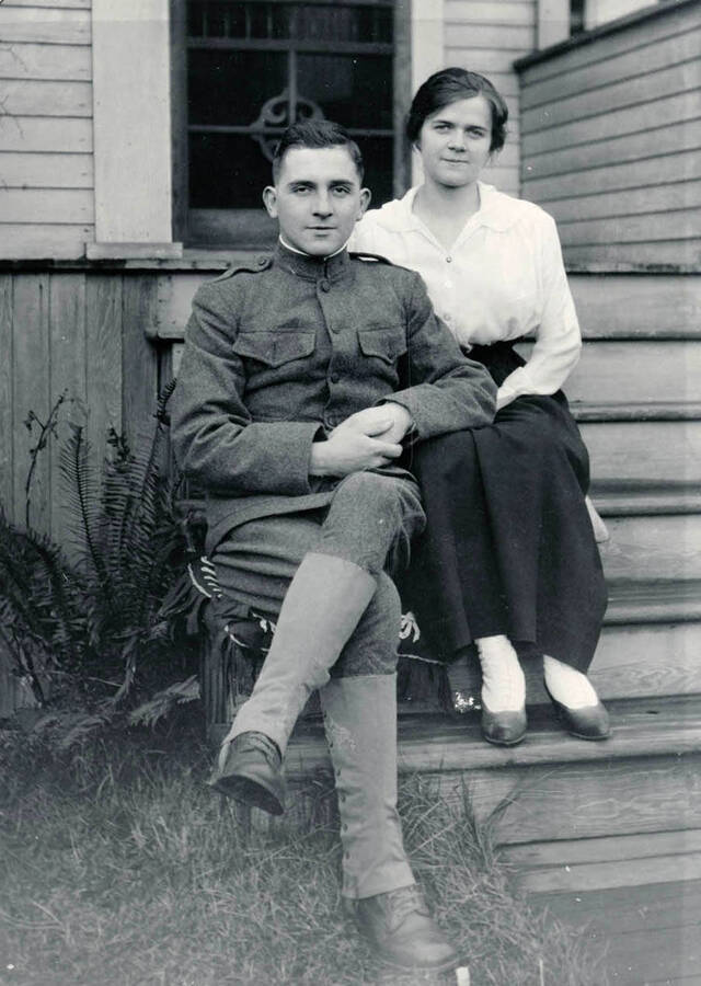 Durell and Mary Bysegger Nirk sit on a porch for a photograph. Both individuals are sitting on cushions on top of steps.