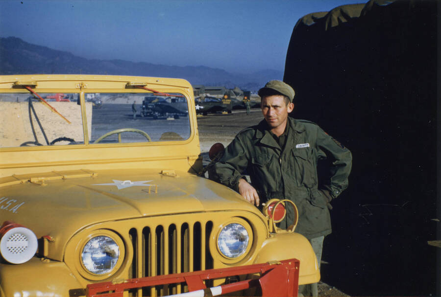 Norman Soncarty standing near bright yellow Army Jeep