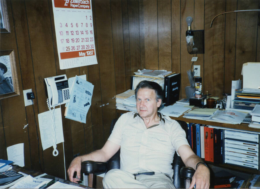 Photo of Larry Nirk seated in the Nirk's Archery office. May 15, 1987