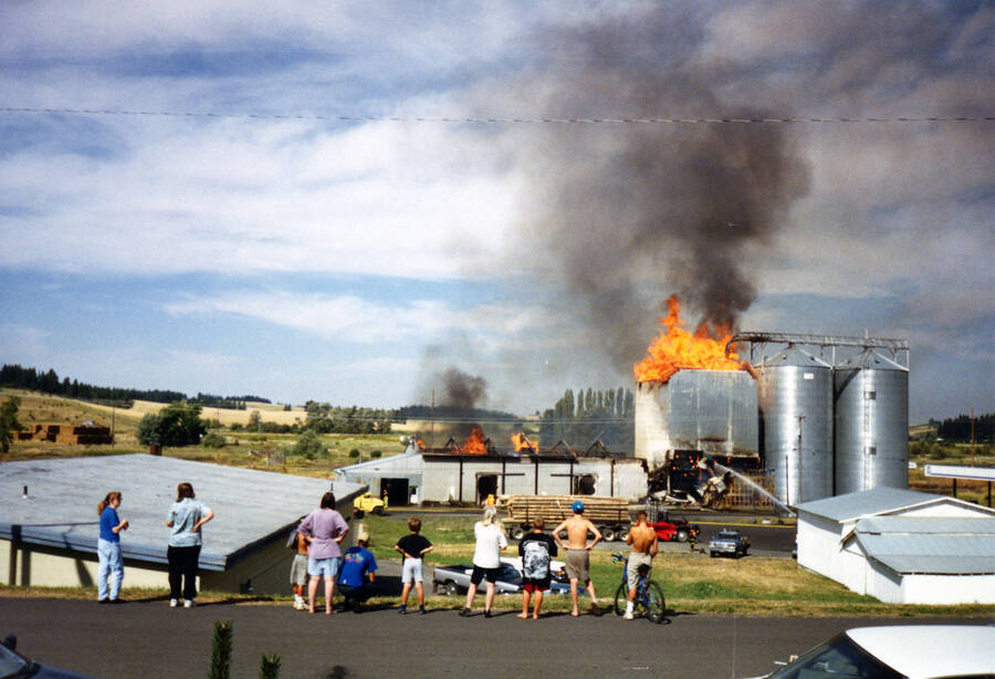 A crowd looks on as firefighters attempt to extinguish a fire that broke out in a silo at Potlatch Grain & Seed.
