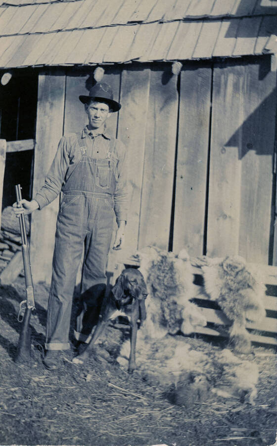 Archie Clark poses for a photograph next to his dog with a few pelts from a hunting trip.
