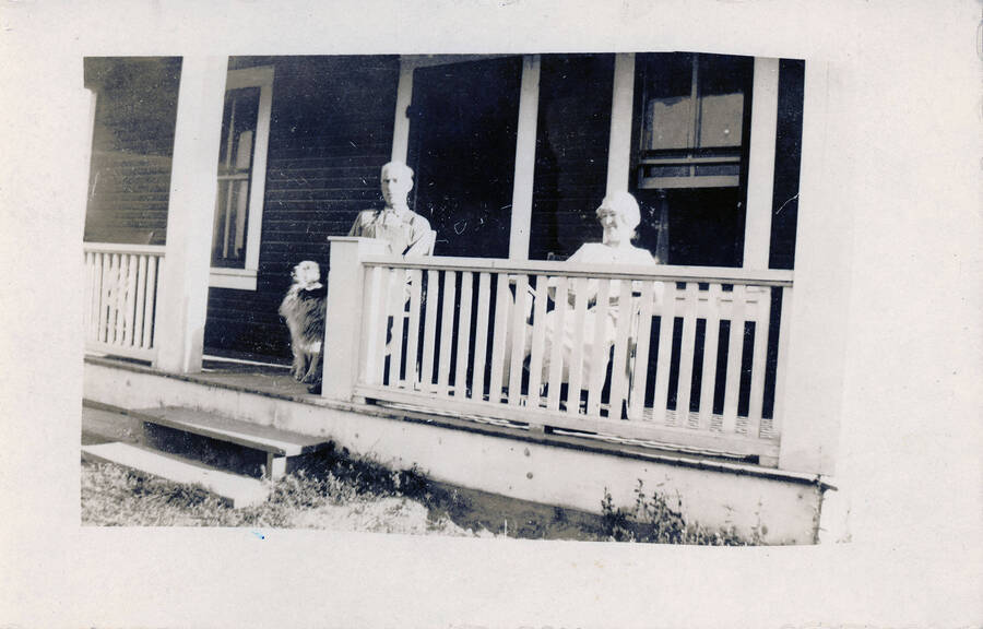 Mr. and Mrs. J.D. Morrissey sit on the porch of their home with their dog.
