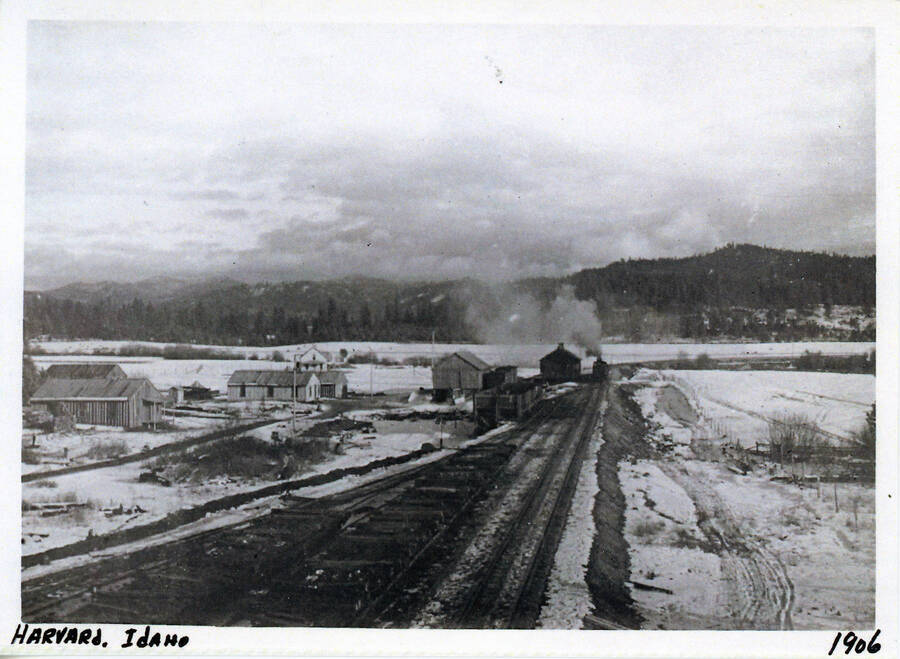 Street view of Harvard, Idaho in 1906. The railroad can be seen at center right in the photo, with a train in the background.