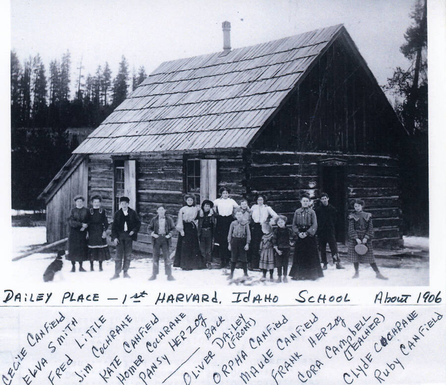 Dailey Place - 1st Harvard, Idaho school. Subjects in photo from left to right: dog, Cecile Canfield, Elva Smith, Fred Little, Jim Cochrane, Kate Canfield, Homer Cochrane, Pansy Herzog, Oliver Dailey, Orpha Canfield, Maude Canfield, Frank Herzog, Cora Campbell (teacher), Clyde Cochrane, Ruby Canfield. 