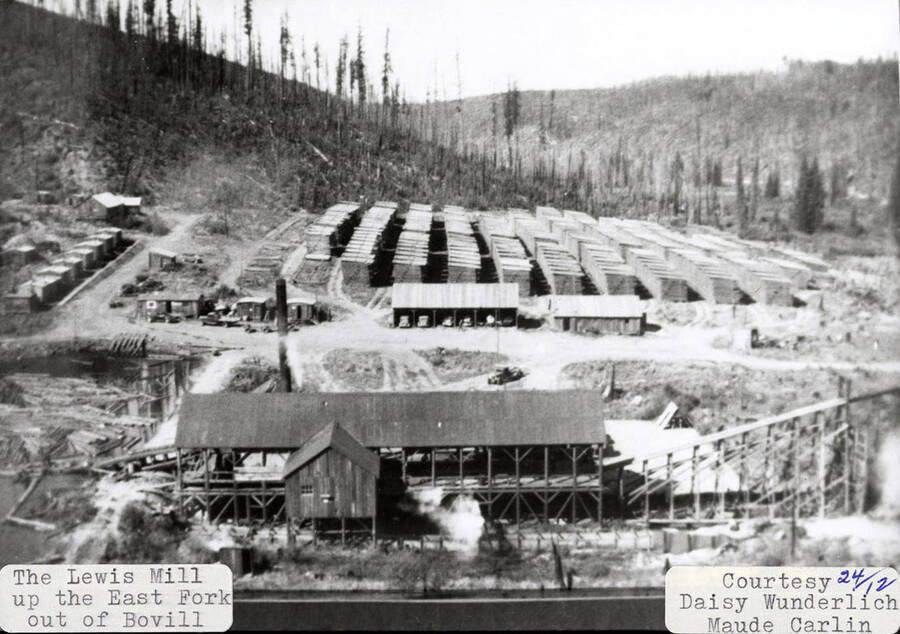 View of the Lewis Mill, which is located up the East Fork out of Bovill, Idaho. Buildings can be seen sitting on the mill, some with cars parked in them.