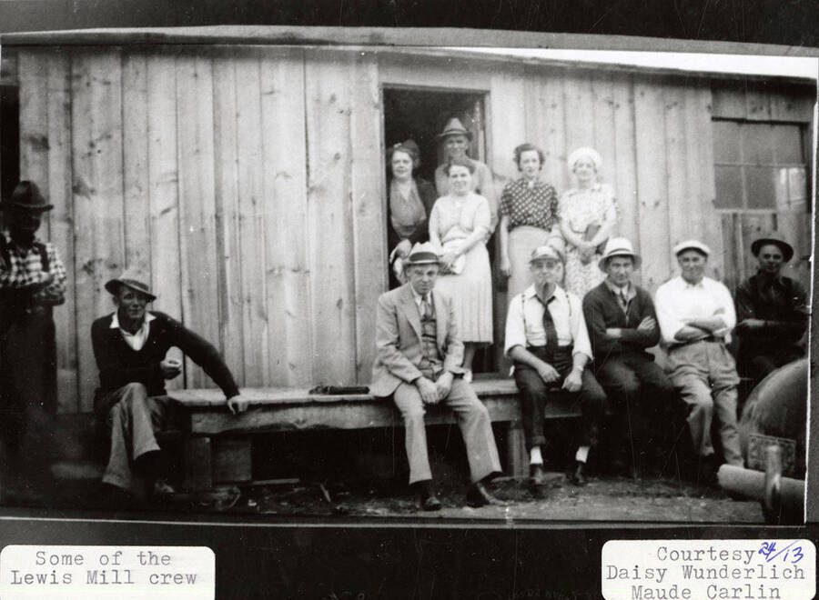 Group photo of some of the Lewis Mill crew. The group can be seen sitting and standing outside the entrance to a building.