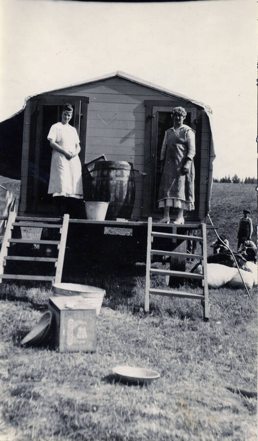 Two women stand on the porch of a cook house.