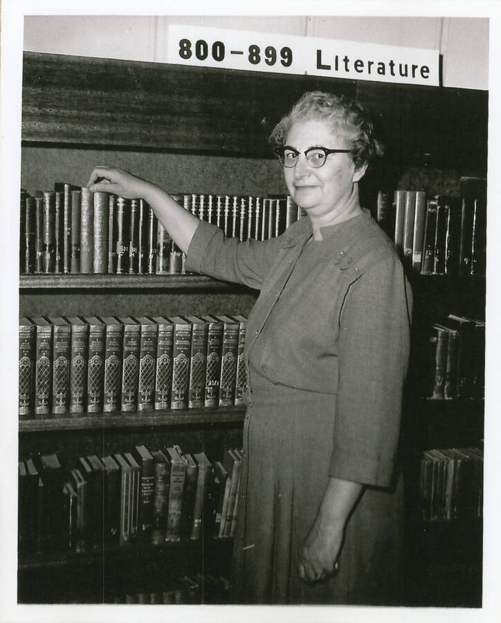 Georgia Mae Bennett in front of library shelves. She taught at Potlatch High School.