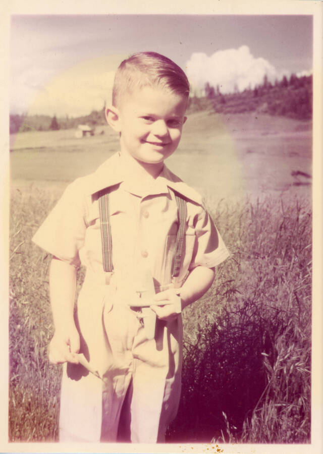 Photograph of a young Gary E. Strong in a field at home in Potlatch.