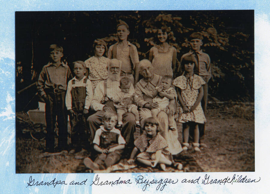 Photograph of Gottfried and Anna Bysegger with their grandchildren. Back Row: Glen Nirk, Isla and Eugene Bysegger, Cleora Nirk, Gerald Nirk; Middle Row: Max Davis, Gottfried Bysegger holding John Bysegger, Jr., Anna Bysegger holding Norman Soncarty, Leola Nirk. Front Row: Lowell Soncarty, Norma Jean Nirk.