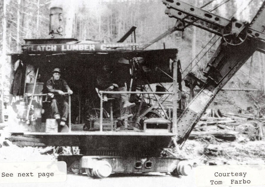 A few men sitting inside the steam shovel machine.