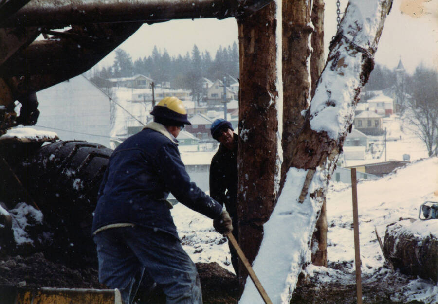 Photograph of Buzz Bringlson and Wahyn Himmelman dismantling the green chain at the Potlatch Mill.