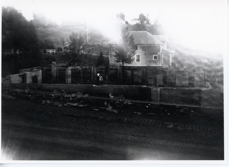Photograph of the Community Presbyterian Church walls remaining after the fire with the parsonage showing behind.