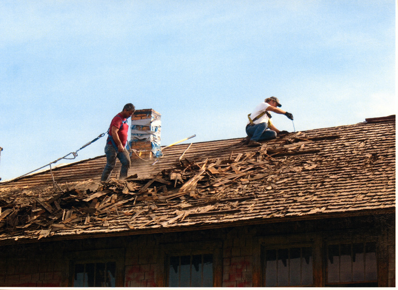 Photograph of men removing shingles from the roof of the WI&M Depot.