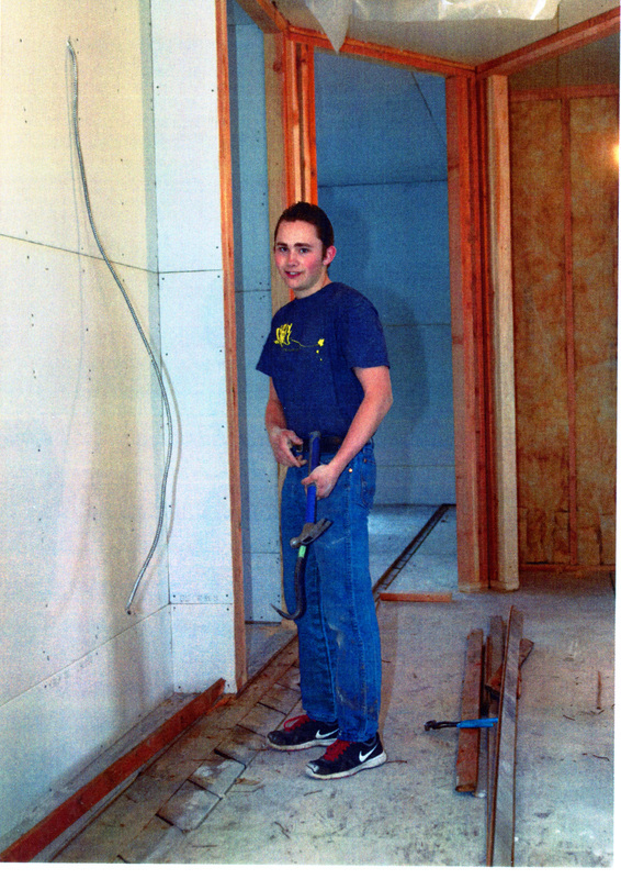 Photograph of a young man hanging sheetrock on the 2nd floor of the WI&M Depot.