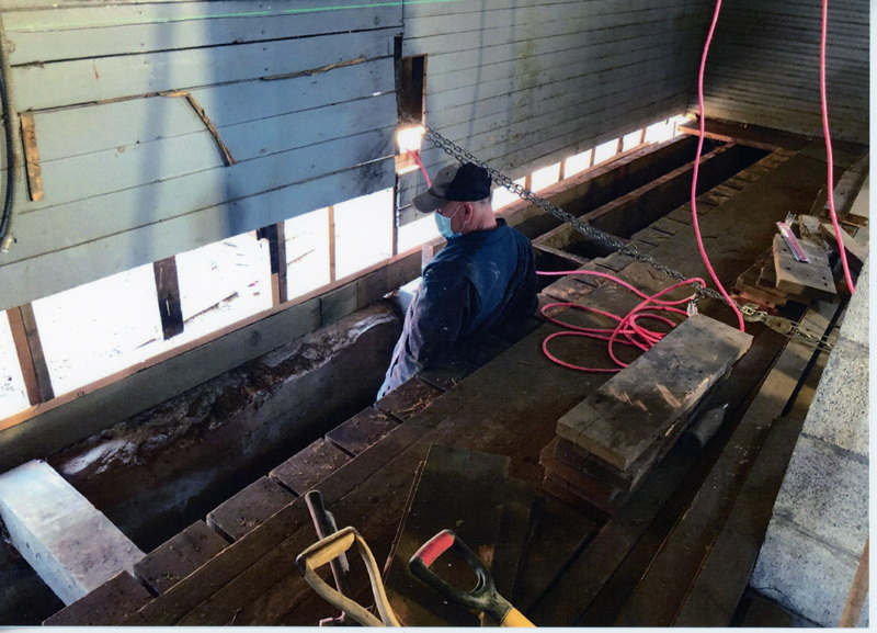 Photograrph of man restoriing the foundation and floor of the WI&M Annex.