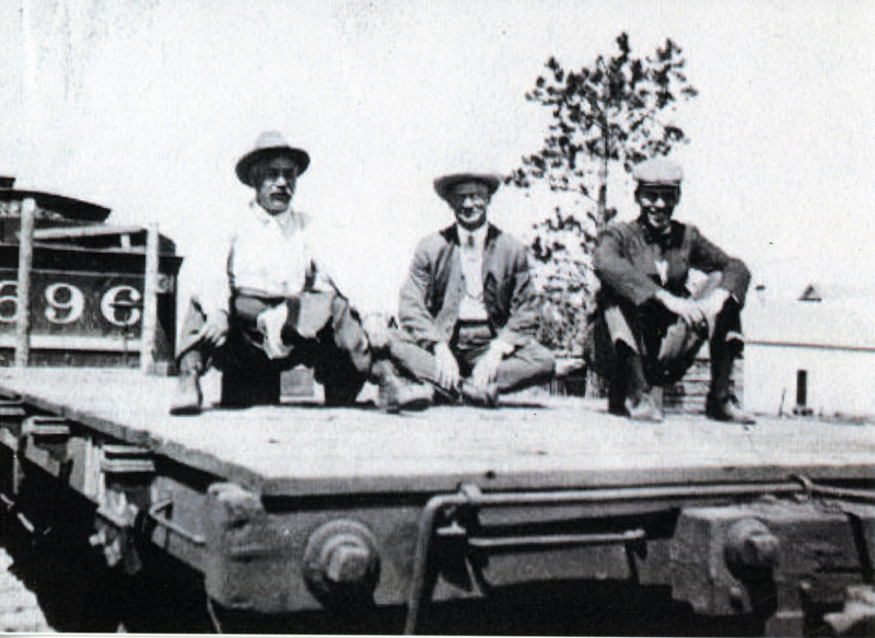 Photograph of William Deary, F.S. Bell, and Laird Bell sitting on a flatcar.