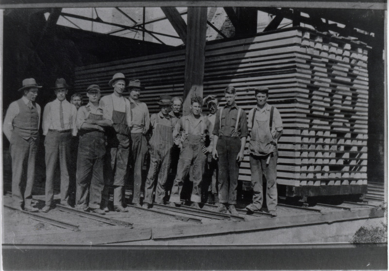 Photograph of men with lumber at the dry kiln at the Potlatch Mill.