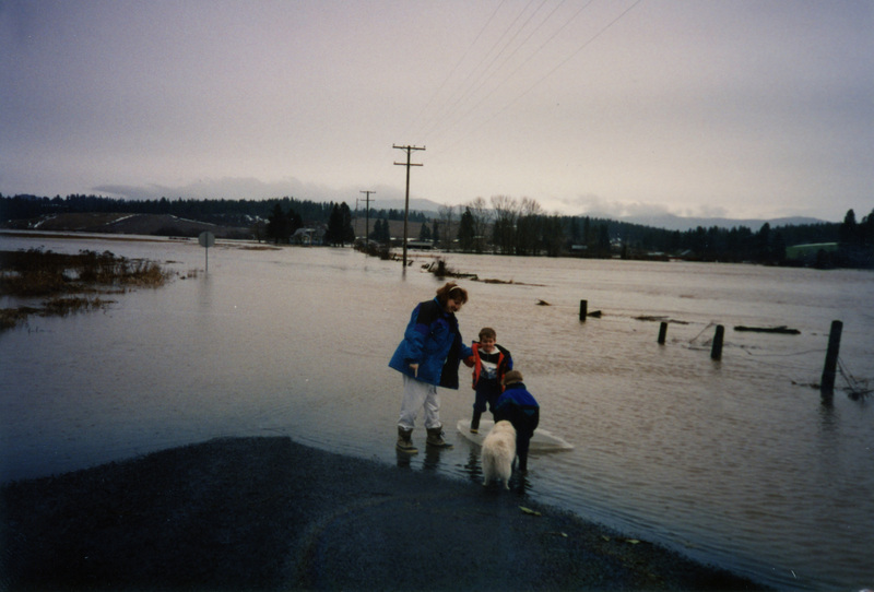 Photograph of a woman, child, and dog near a flood in Potlatch.