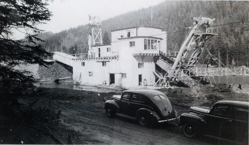Photograph of a car in front of the gold dredge on the Palouse River.