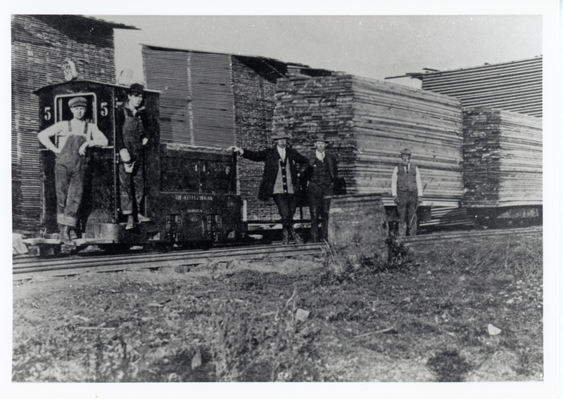 Photograph of a Jeffrey battery locomotive #5 pulling lumber to the drying yard.