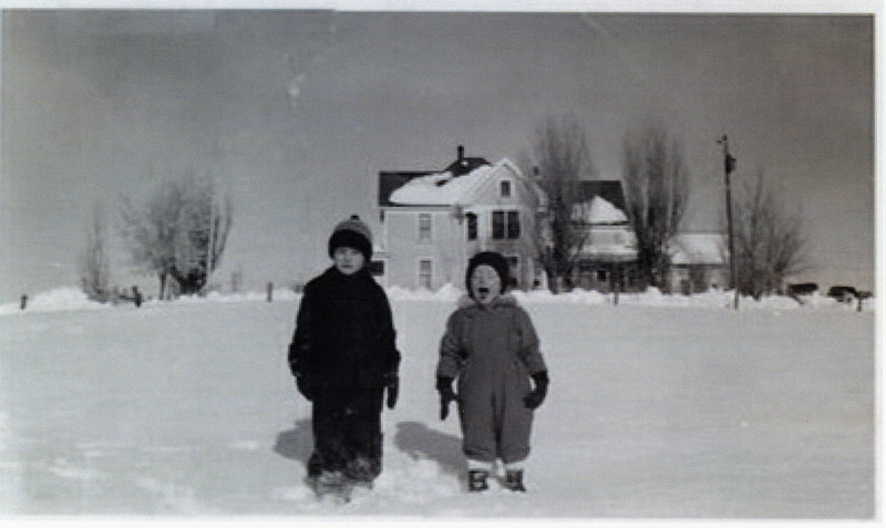 Photograph of children standing in the snow in front of the Rohn home on Yellow Dog.