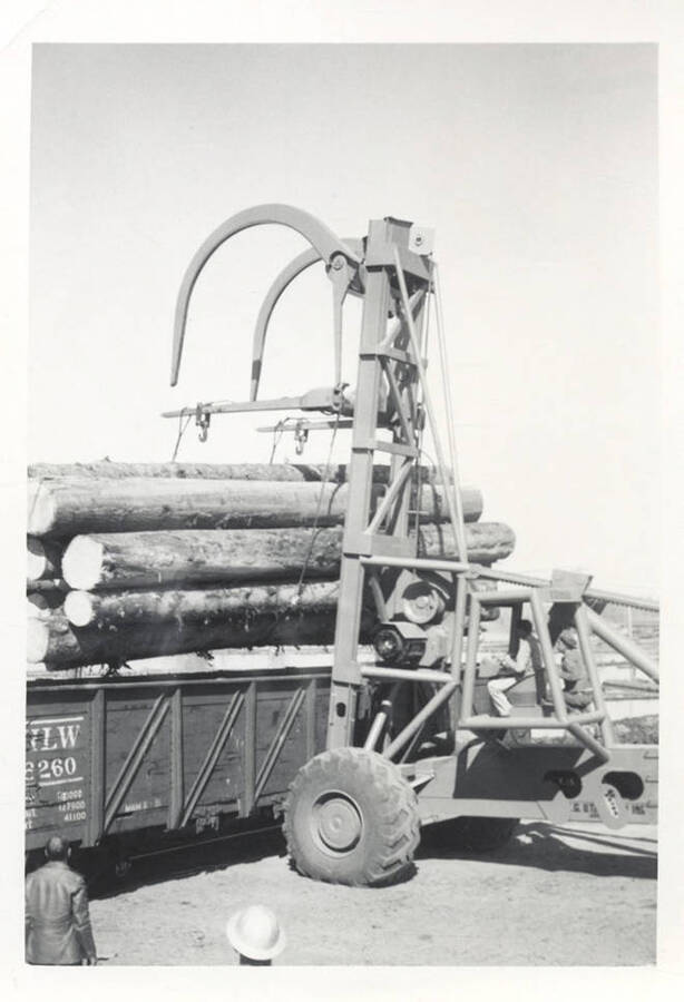 The LeTourneau log unloading machine lifting logs from a train car.