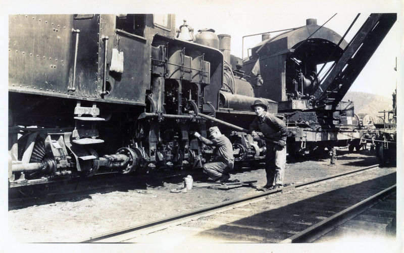 Photograph of Neil Discol working on a shay at Camp 8; Marion on a Wi&M flat car is beyond.