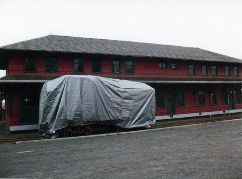 Photograph of Caboose X-5 under a tarp at the WI&M Depot in Potlatch.