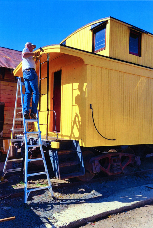 Photograph of Bob Behal installs ladder brackets on the Caboose X-5 at the WI&M Depot at Potlatch.