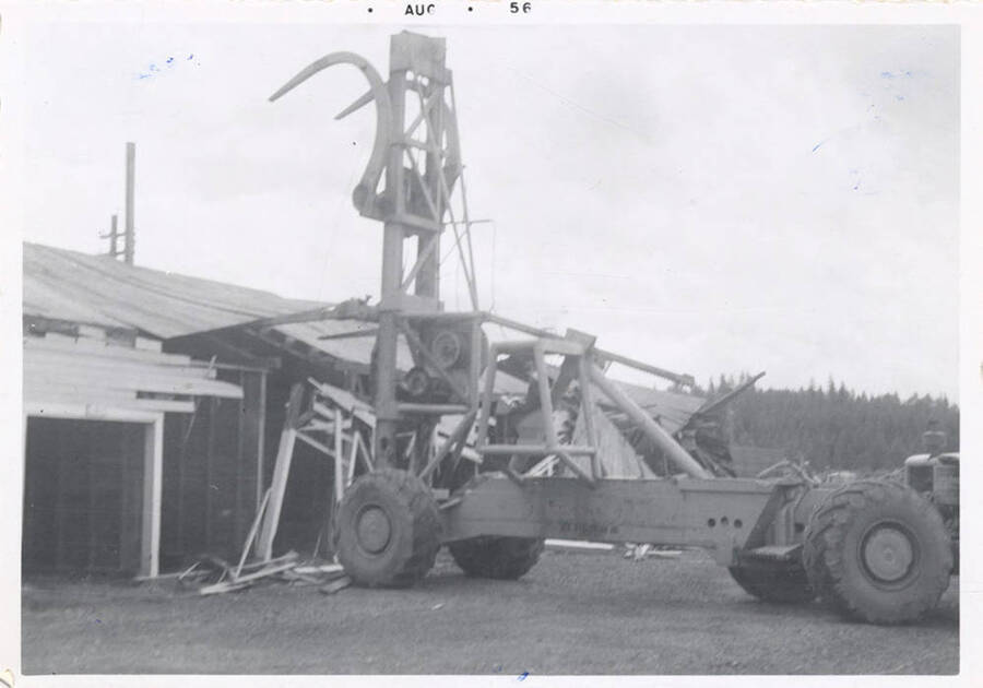 The LeTourneau log unloading machine beginning to take off the rooftop of a structure.