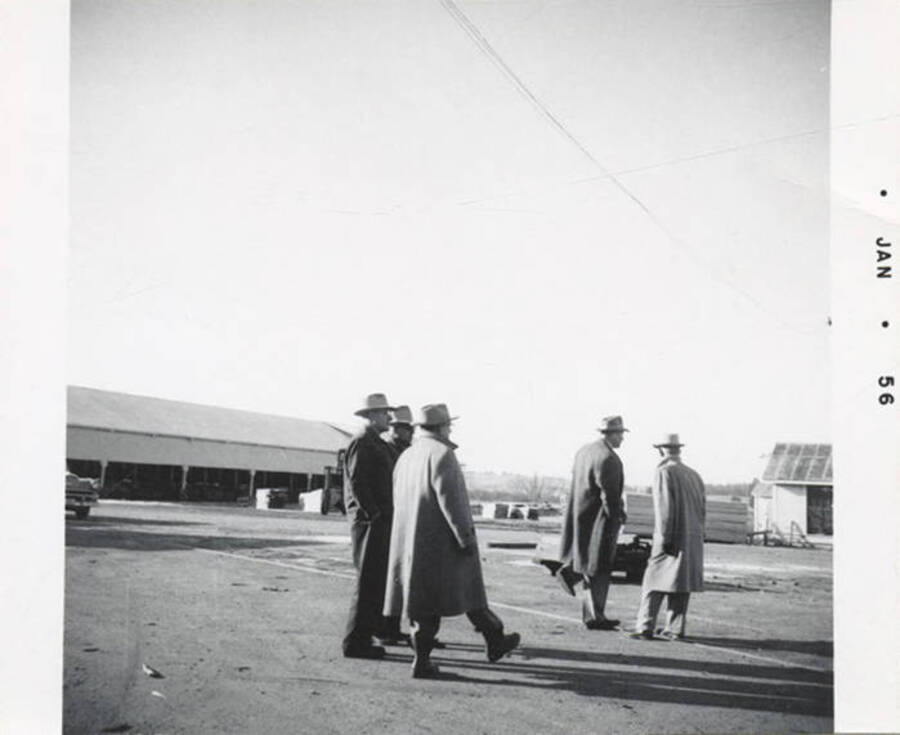 A photograph of fie men in their coats and hats walking.