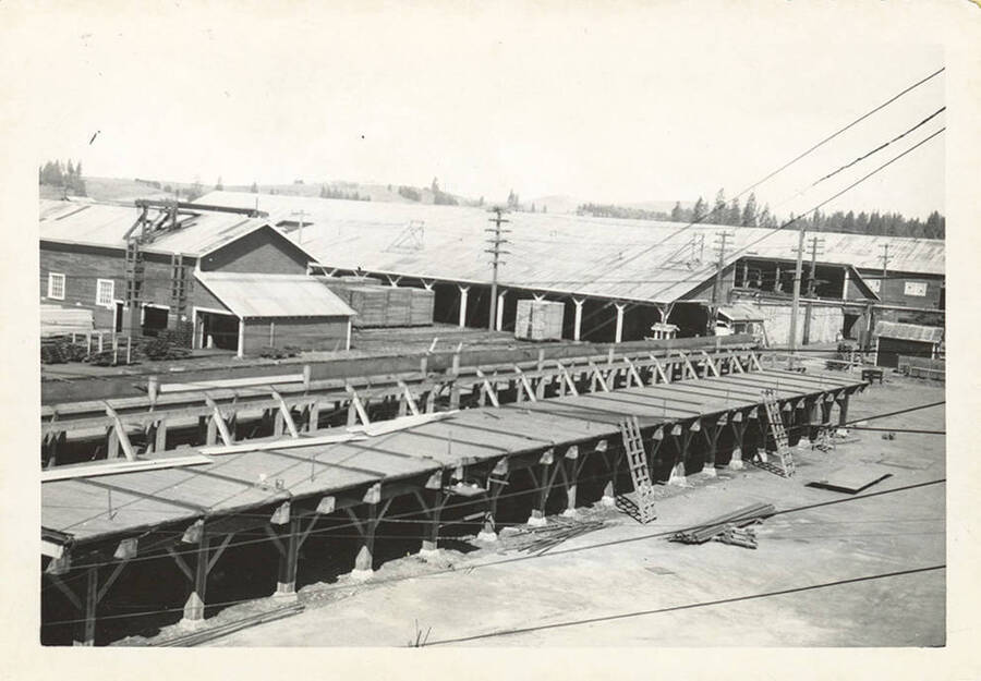 A photo of a structure and some buildings at a lumber mill.