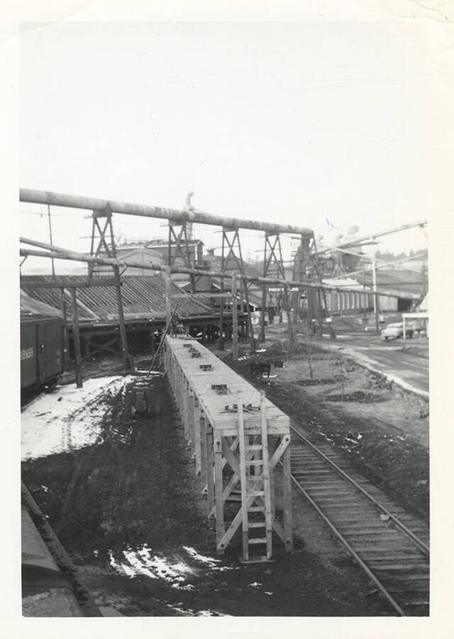 A photograph of railroad tracks, a platform, and piping.
