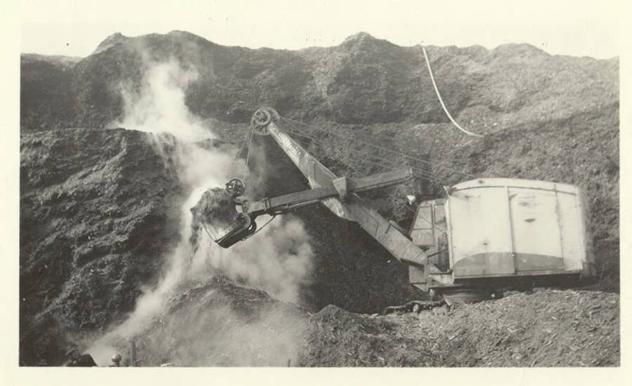 An excavator removing dirt from the side of a hill.