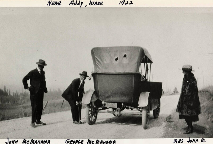 John McManama, George McManama, and Mrs. McManama next to their vehicle.  Photograph taken in 1922, near Addy, Washington.