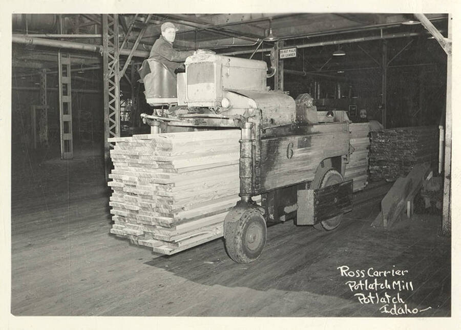 A photograph of a worker running the ross lumber carrier at the Potlatch mill.