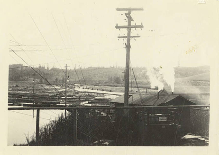 A view of power lines and steam coming from a building.