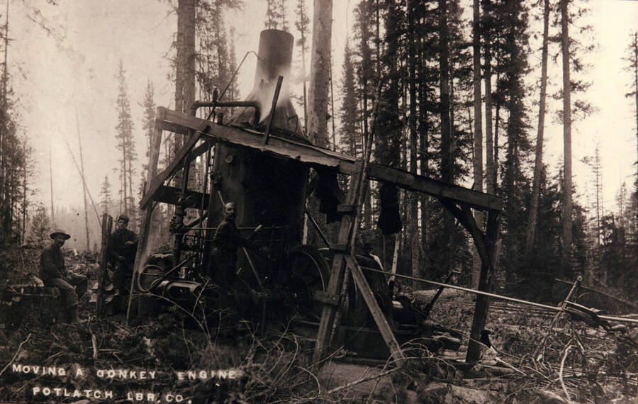 Three employees moving a donkey engine for the Potlatch Lumber Company.