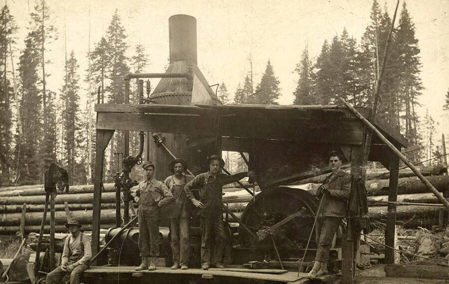 A photograph of Elk River Mill employees o a machine that appears to move logs.