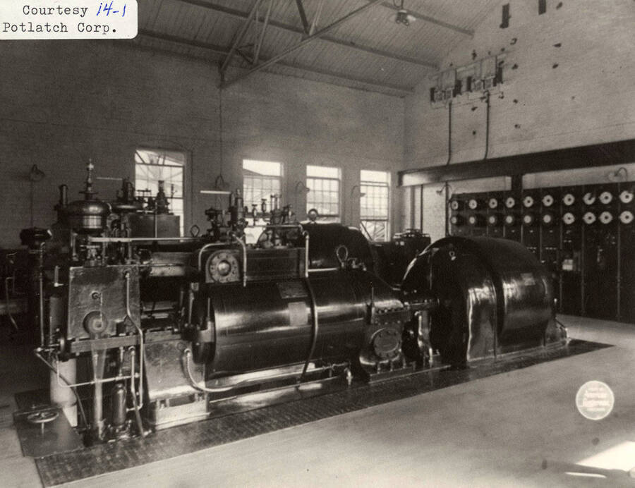 This photo shows the electric generating equipment at the Elk River plant, installed in 1910. It was the source of all electric power for the entire mill, and in the 'early days' to the town, in the evening hours, as well. The two generators and Parsons type steam turbines were built by Westinghouse. One unit, serial No. 801, was rated at 625 K.V.A the other with serial No. 766, was rated at 1000 K. V. A. Both operating at 600 volts, 3-phase, 60 cycles and 3,600 R.P.M. After Elk River was closed down the larger unit was moved andinstalled at the Potlatch mill, and was then reqired to suppply 2400 volts. Originally the each cost around $17 and $20,000.00.