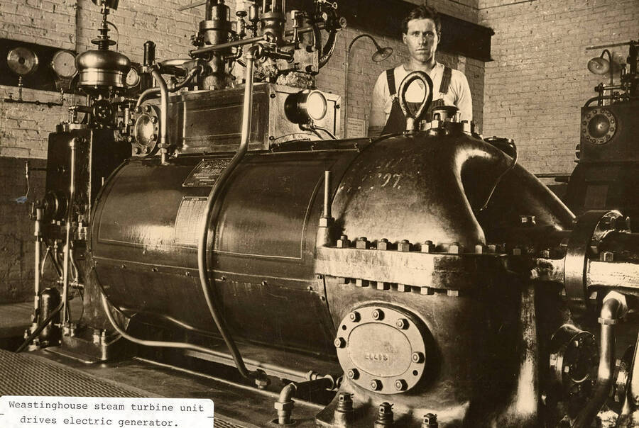 A photograph of an employee and the Weastinghosue steam turbine unit that drives the electric generator.